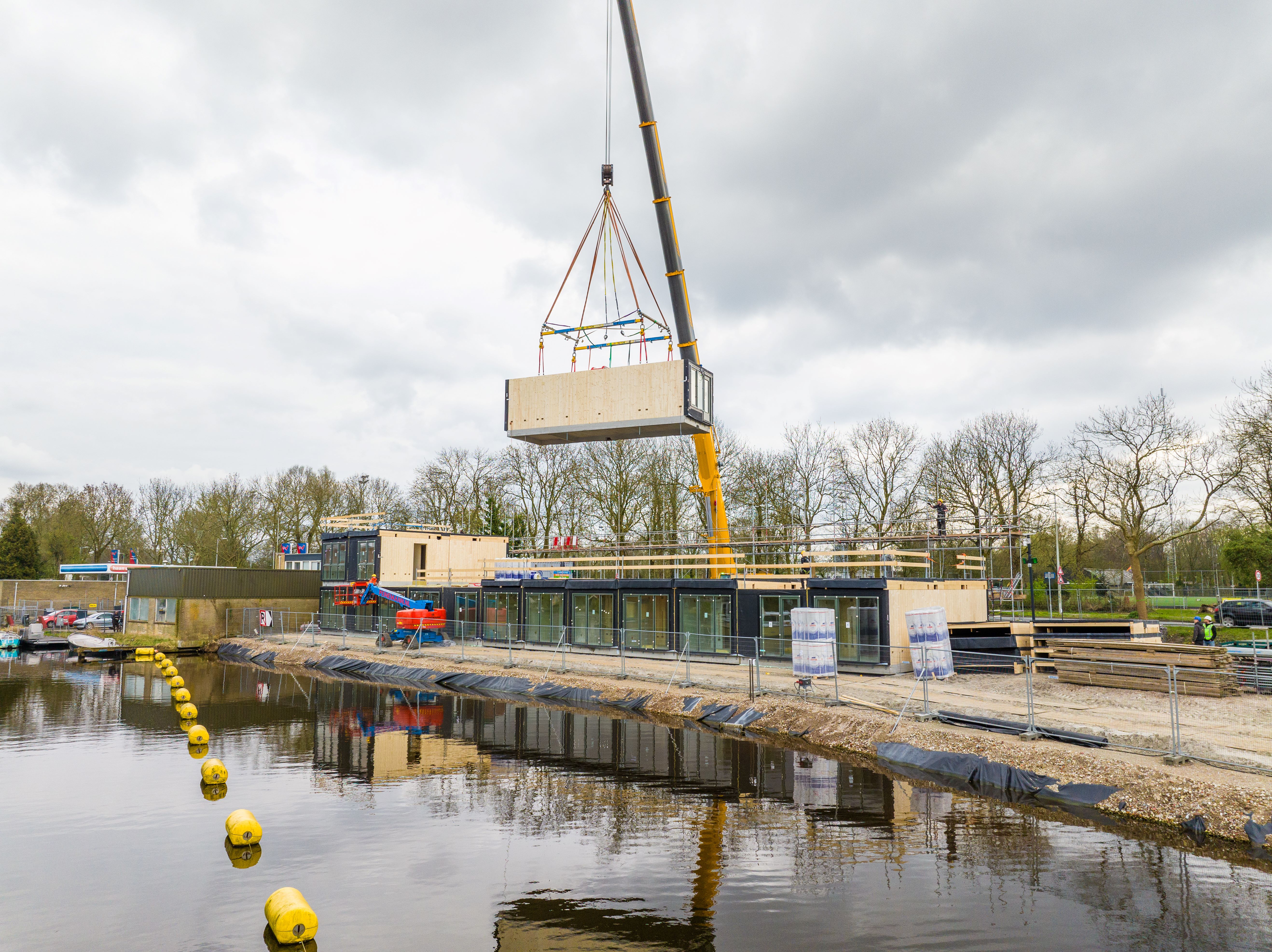 Module woning in de kraan op bouwplaats aan het water