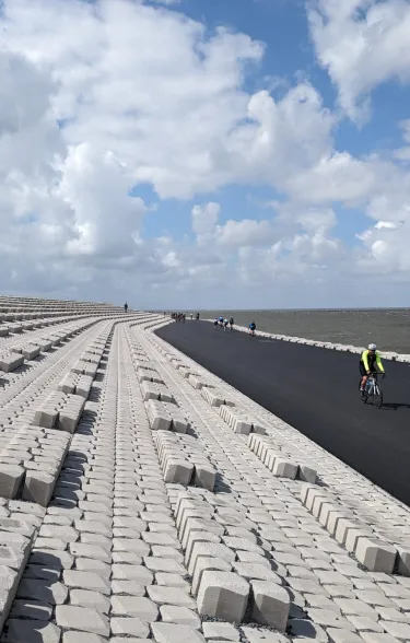 Wielrenners over de Afsluitdijk langs de Basalton blokken van Holcim Coastal