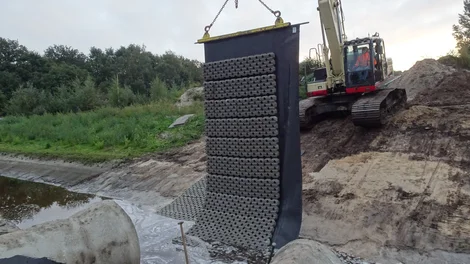 Hijsen van de betonblokkenmat met grasbeton tegels voor oeverversteviging