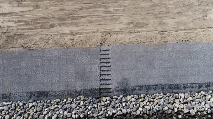 Luchtfoto van een trap in de verstevigde dijk met de Basalton STS zuilen van Holcim