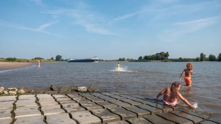 Kinderen spelen in het water bij een hellingbaan van Betonblokmatten