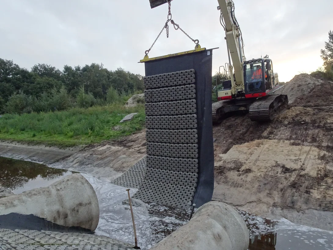 Hijsen van de betonblokkenmat met grasbeton tegels voor oeverversteviging
