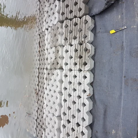 Het op maat snijden van het geotextiel onder de grasbetontegels van de betonmatten