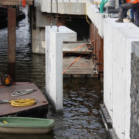 De prefab deksloven hangen in de kraan om op de damwand te plaatsen