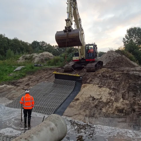Leggen van de Betomat PE-GR (betonblokkenmat grasbetonblokmat) voor oeverversteviging