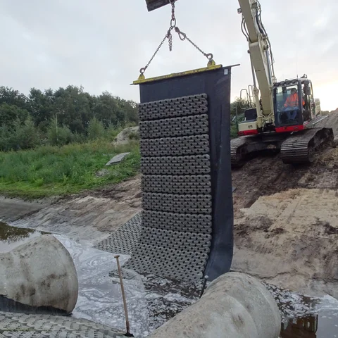 Hijsen van de betonblokkenmat met grasbeton tegels voor oeverversteviging