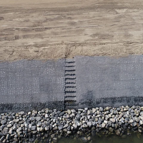 Luchtfoto van een trap in de verstevigde dijk met de Basalton STS zuilen van Holcim