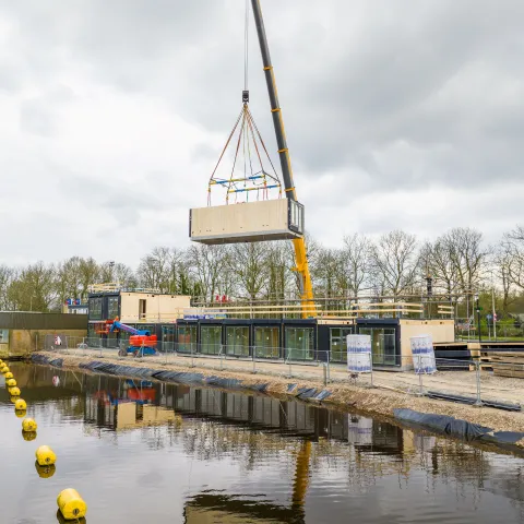 Module woning in de kraan op bouwplaats aan het water